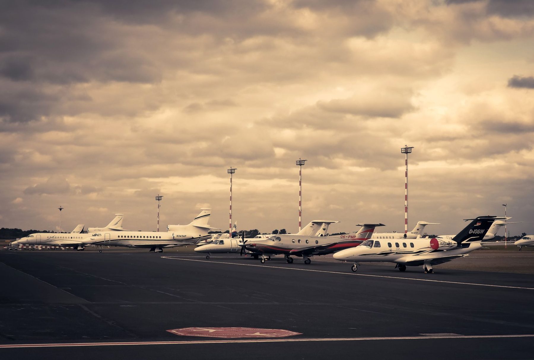 Row of private jets parked on an airport apron under a dramatic sky