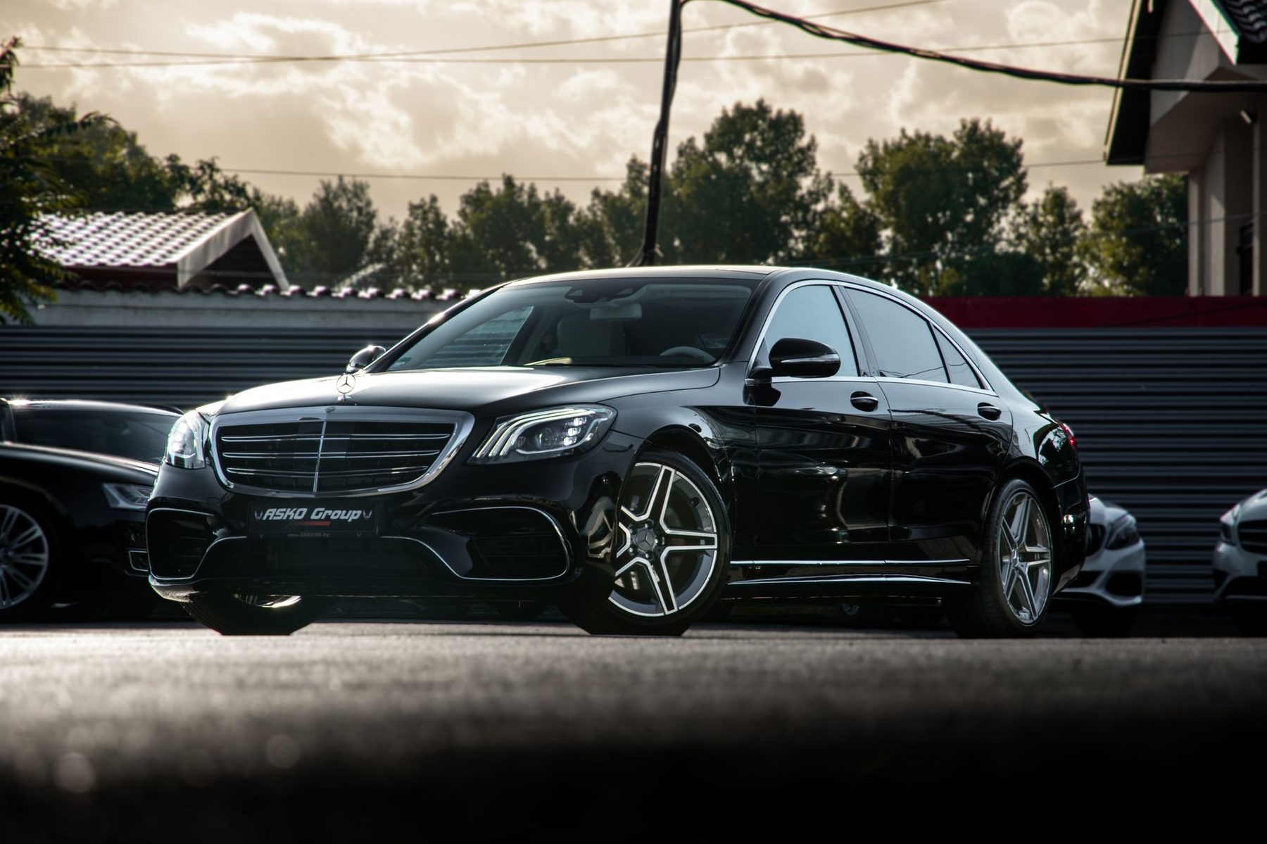 Black Mercedes-Benz S-Class saloon waiting on a city street at dusk
